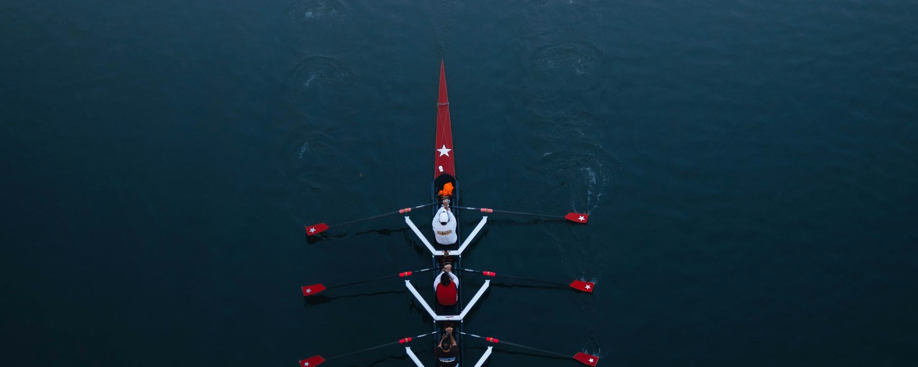 A rowing four seen from directly above on dark water