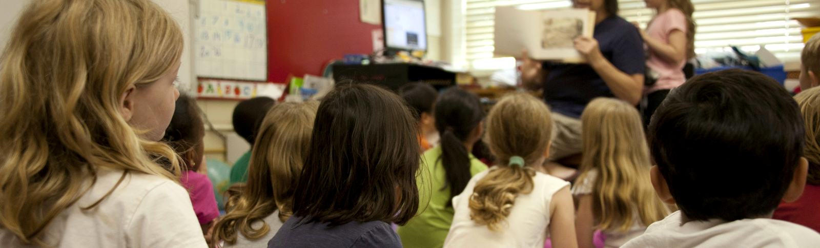 A teacher reading to a class seated on the floor