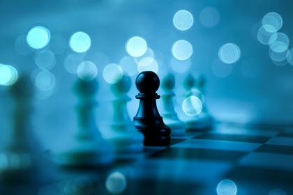 A single dark chess piece among blurred pieces